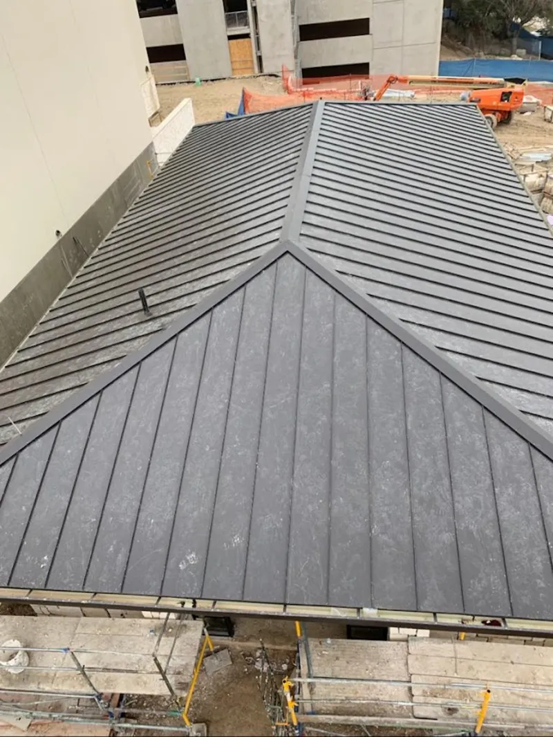 Commercial metal roof construction with crane equipment in Wolcott